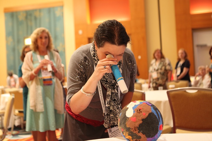 Woman engaging with an interactive activity at a conference. Other people visible in the background.