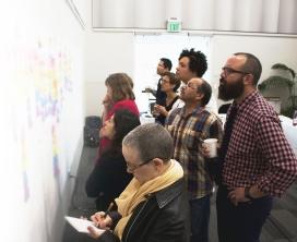 People reviewing a wall of post-it notes