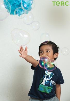 A Latinx elementary-school-aged boy playing with bubbles.